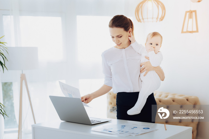 Time to eat. Attentive female person looking at her gadget while spending time with child