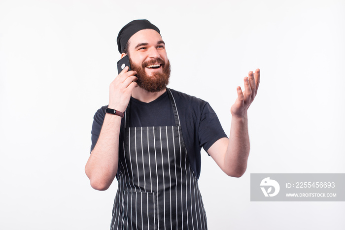 Photo of happy chef man talking on phone and gesturing.