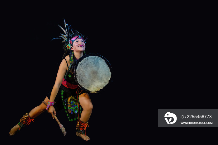 young woman Teotihuacana, Xicalanca - Toltec in black background, with traditional dress dance with a trappings with feathers and drum