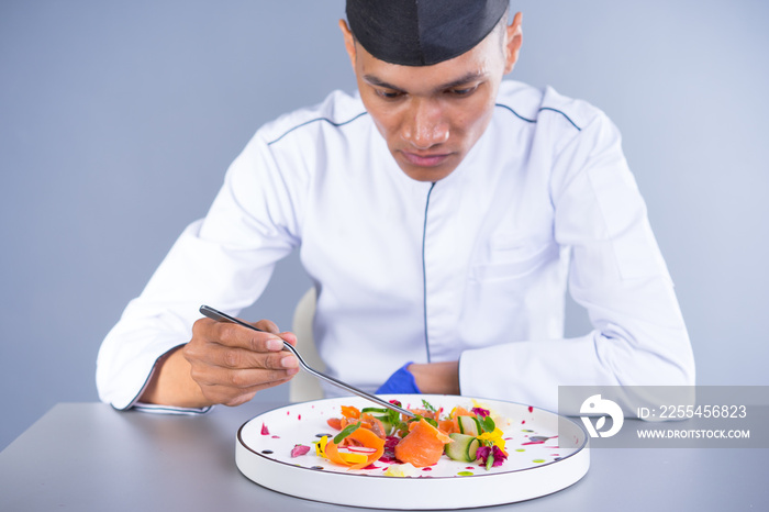 An Asian Executive Chef plating his dish carefully putting his finishing touch to the vibrant dish.