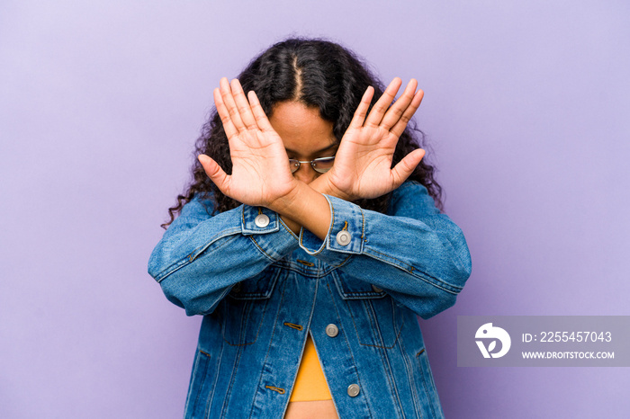 Young hispanic woman isolated on purple background keeping two arms crossed, denial concept.