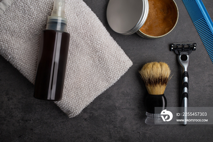 Top view flat lay of shaving accessories and skincare stuff for man on table against dark cement background