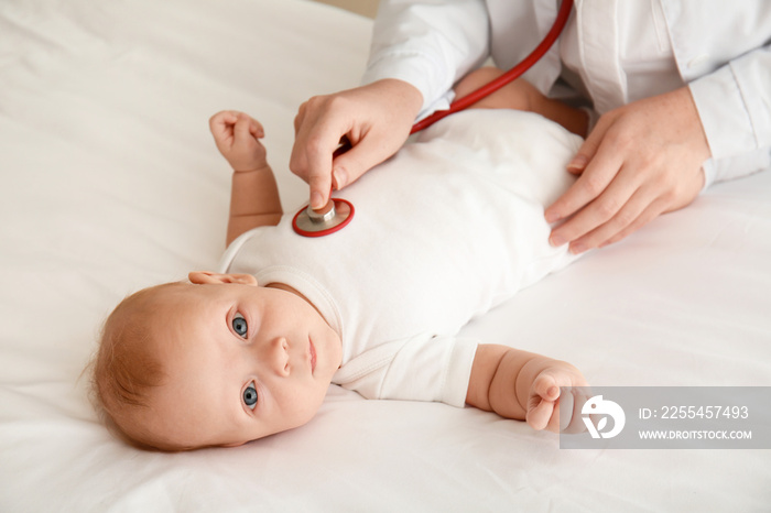 Pediatrician examining cute baby in clinic