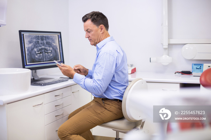 Portrait of happy dentist using mobile phone