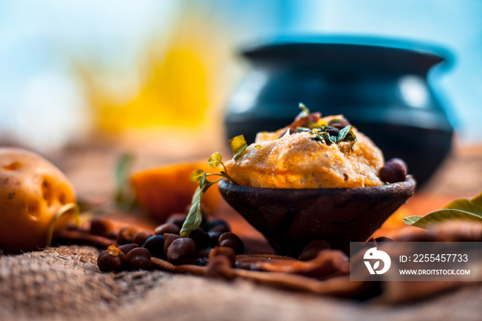 Famous Indian & Asian street food dish i.e. Golgappa snack in a clay bowl along with its flavored spicy water in another clay vessel. Horizontal shot of the snack and its ingredients present.