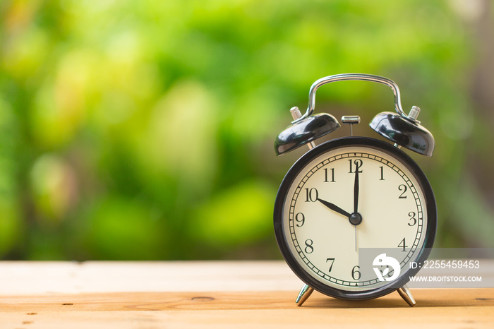 clock on wood table in the green garden time at 10 o’clock