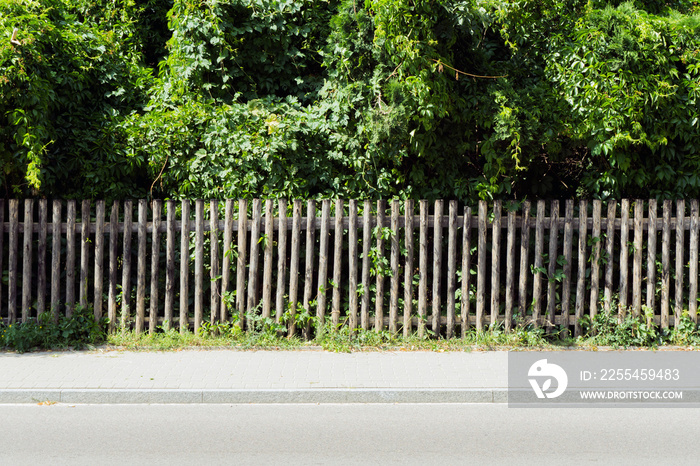 Village fence background. Rustic wooden property border. Green trees in home garden. Countryside forest wooden fence. Outdoor park texture.