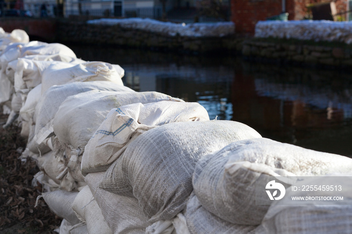 Temporary dam made of white sandbags prevention river flooding extreme weather danger safety emergency fire brigade environmental disaster