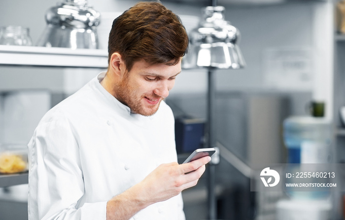 cooking, profession and people concept - male chef cook with smartphone at restaurant kitchen