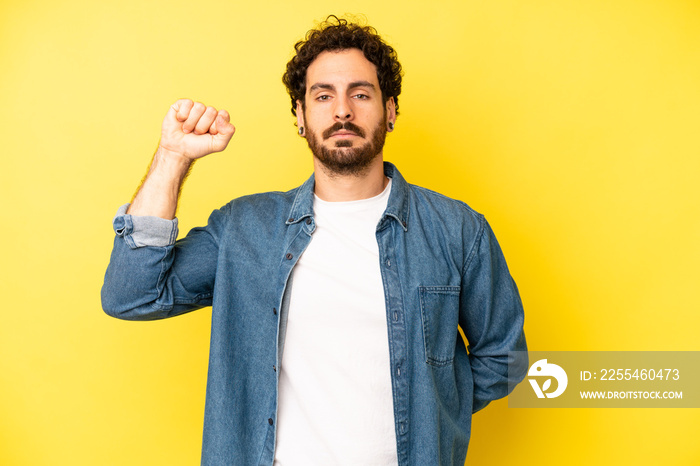 young bearded man feeling serious, strong and rebellious, raising fist up, protesting or fighting for revolution