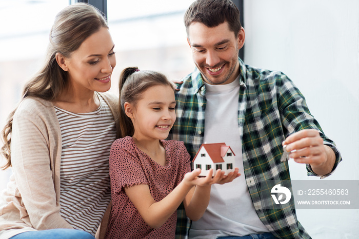 mortgage, family and real estate concept - happy mother, father and little daughter with house model and stuff in boxes moving to new home