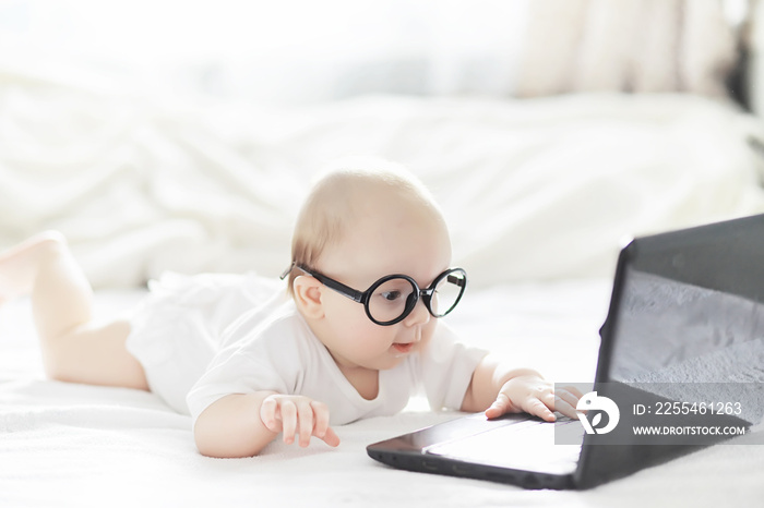 A newborn baby is lying on a soft bed in glasses.