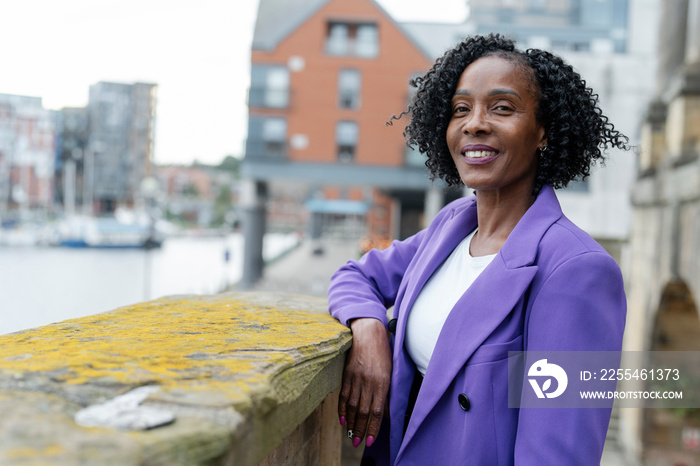 Portrait of smiling woman standing by riverbank