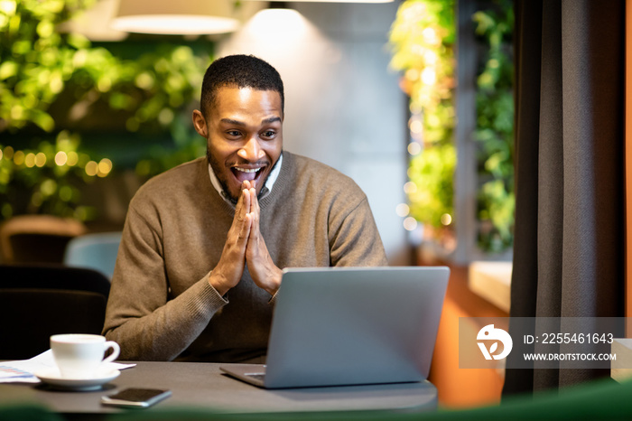 Black businessman using laptop sitting at cafe