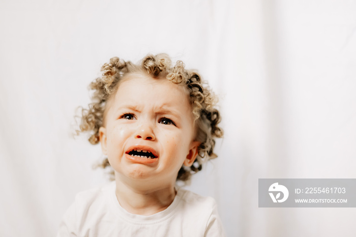 Portrait of beautiful baby girl crying emotionally. Child emotions and child crying