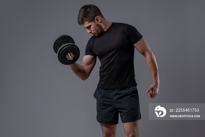 Sporty guy performing biceps curl with dumbbell