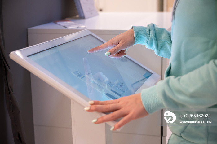 Faceless woman touching the screen of a self-service device in a store. Device store navigator. Self purchase.