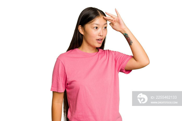 Young Asian woman isolated on green chroma background looking far away keeping hand on forehead.