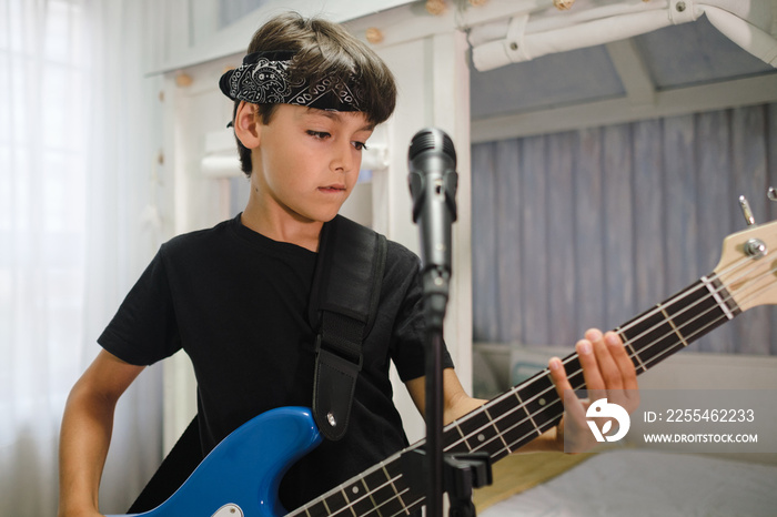 Close up of rocker child practicing with the bass at home.