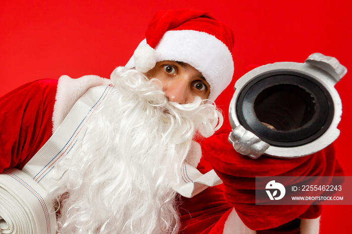 Christmas man in santa clothes with fire Hose standing against isolated red background