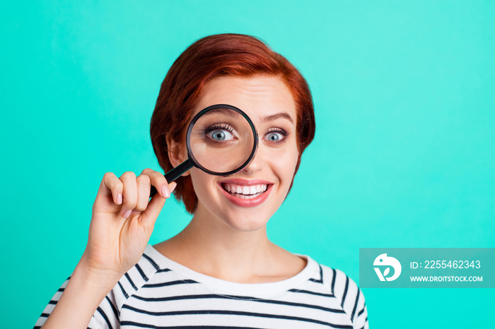 Close up portrait of attractive she her lady with optical lupa in hand looking one eye through it wondered surprised wearing white striped sweater isolated on teal background