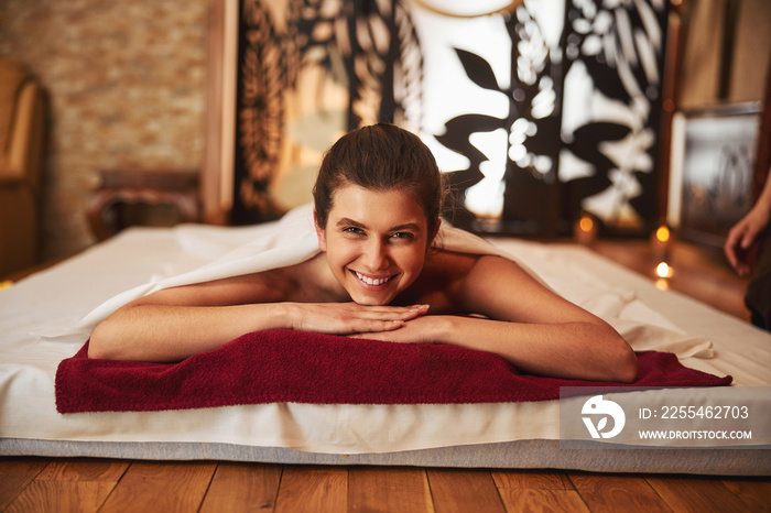 Smiling woman in massage centre with hands under her head