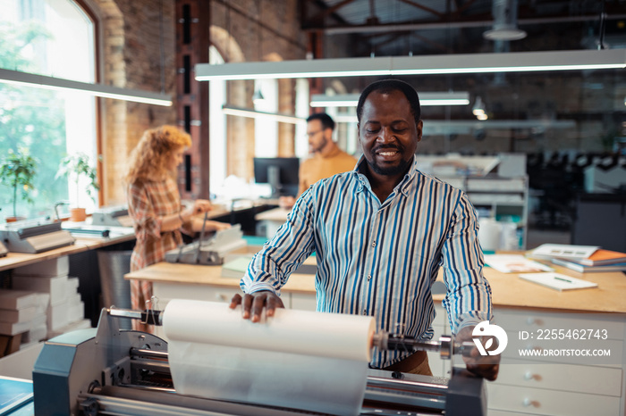 Dark-skinned bearded man feeling involved in printing posters