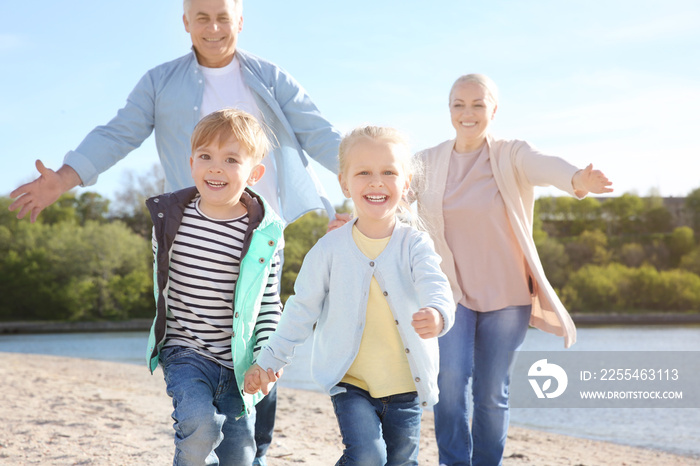 Happy grandparents playing with little children on river bank