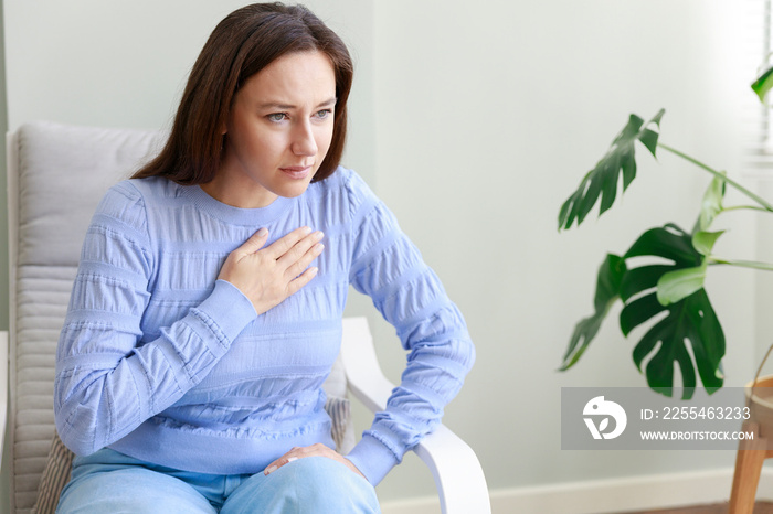 Young woman suffering from a chest pain and touching her heart.