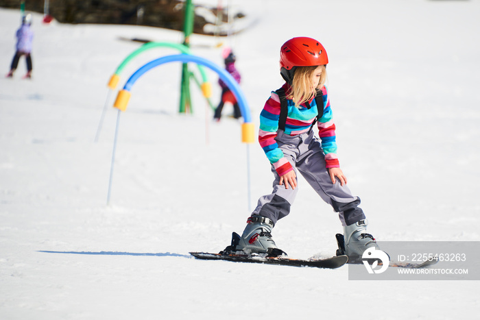 Child girl skiing in mountains. Active kid with safety helmet and goggles. Ski race for young children. Kids ski lesson in alpine school. Little skier racing in snow