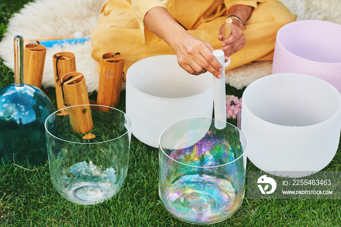 Woman playing music on crystal singing bowls, relaxing in beautiful green garden