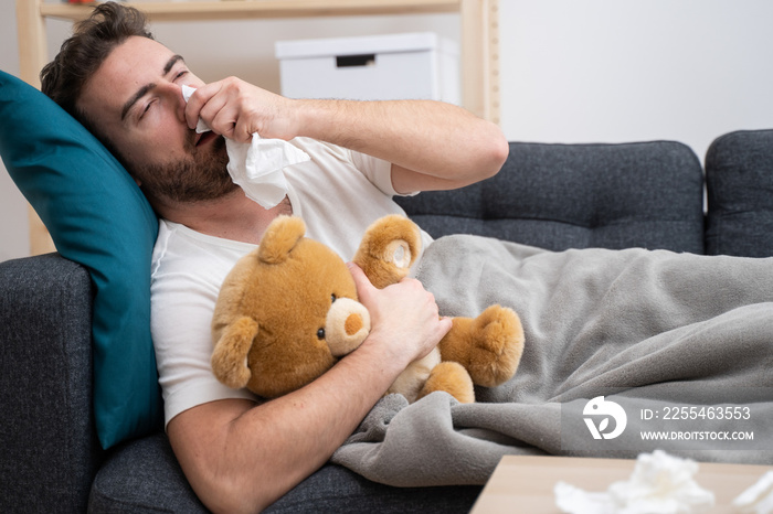 Sick man portrait on the sofa blowing nose