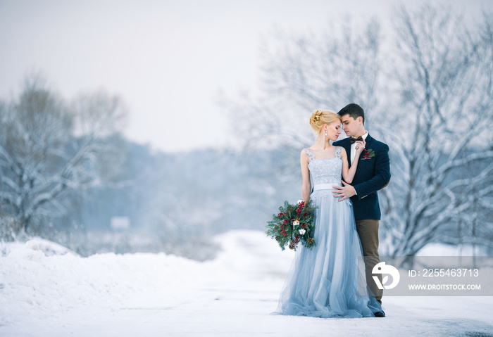 Bride and groom among snowy landscape.