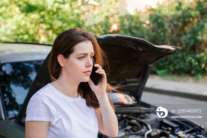 Portrait of frustrated young woman calling mobile phone for help Insurance service or ambulance after car accident. Woman in front of broken car with a mobile phone in hand