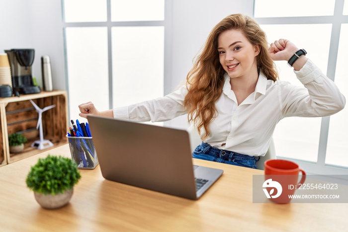 Young caucasian woman working at the office using computer laptop dancing happy and cheerful, smiling moving casual and confident listening to music