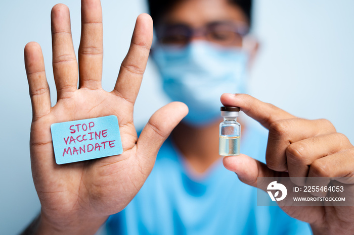 Focus on hands, Young man with medical face mask showing stop vaccine mandate - concept vaccine hesitancy.