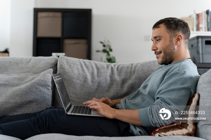 Smiling mature man working on laptop on sofa