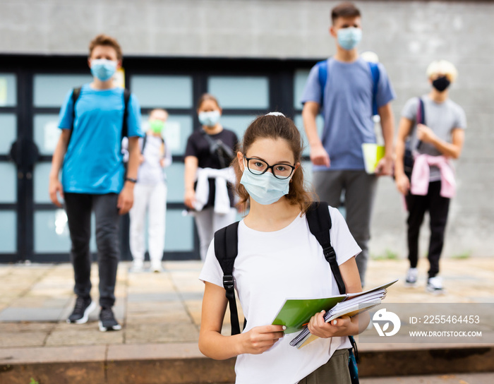 Portrait of teen girl student in face mask on her way to college in warm autumn day. Forced precautions in COVID pandemic.