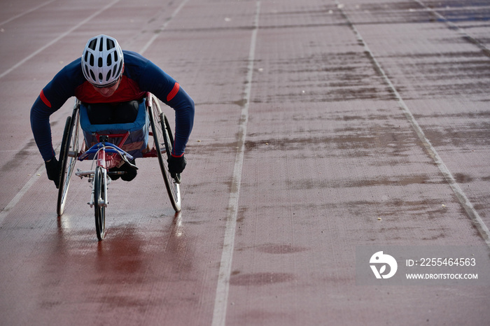 Paraplegic male athlete in racing wheelchair warming up alone outdoors