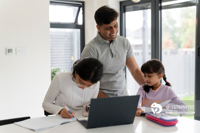 Father helping daughters doing homework