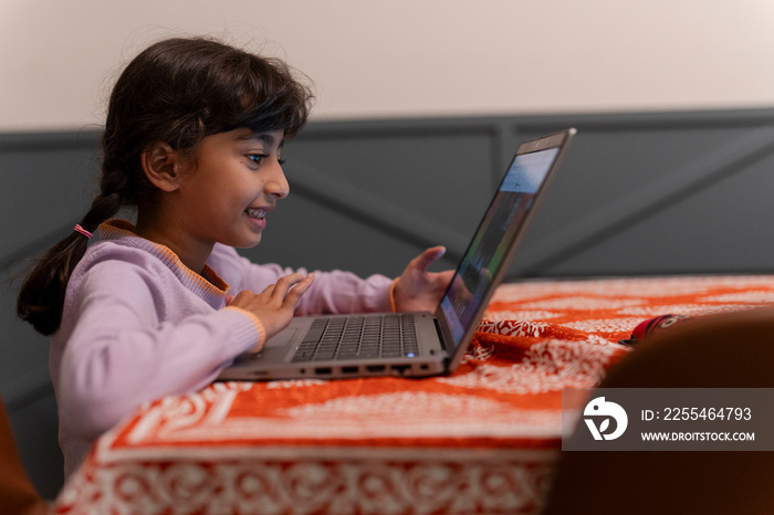 Little girl using laptop at table