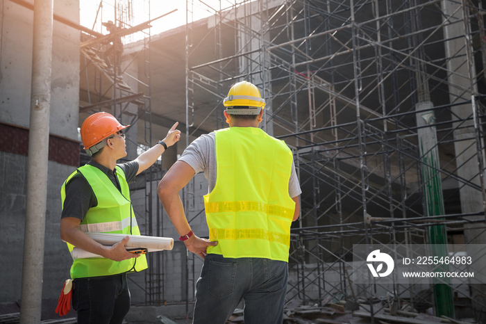 Engineer discussing with foreman about project in building construction site.