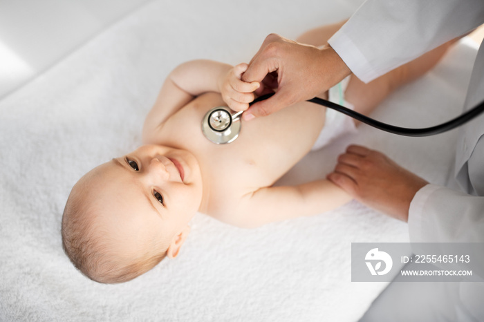 medicine, healthcare and pediatrics concept - close up of female doctor with stethoscope listening to baby girl’s patient heartbeat or breath at clinic or hospital