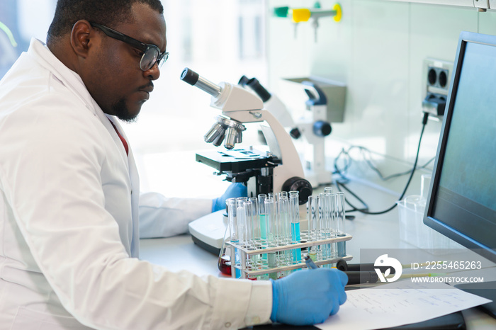 African-american medical doctor working in research lab. Science assistant making pharmaceutical experiments. Chemistry, medicine, biochemistry, biotechnology and healthcare concept.