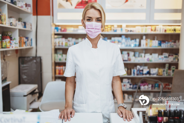 Young and attractive female pharmacist with face protective mask working in drugstore. She is confident and serious. Covid-19 open for business concept.