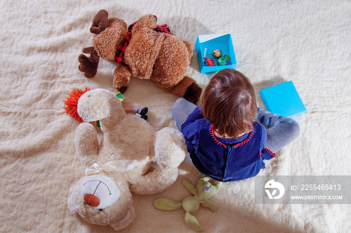 Cute little girl playing with teddy bear and elk. (happy childhood, education, knowledge concept)