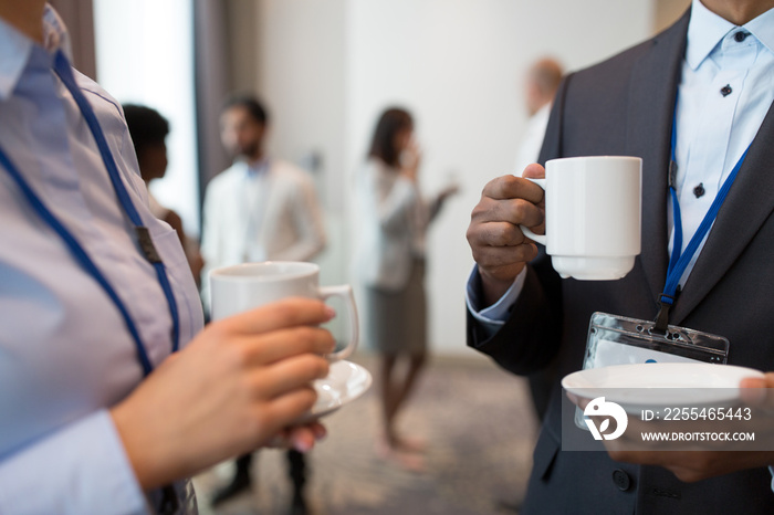 business, communication and education concept - international group of people with conference badges drinking coffee and talking at brake