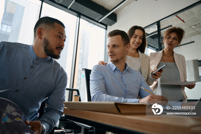 Team of men and women are talking in spacious office