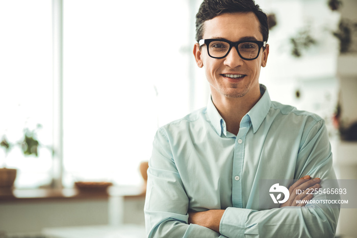 Positive mood. Positive smart man looking at you while being in the office