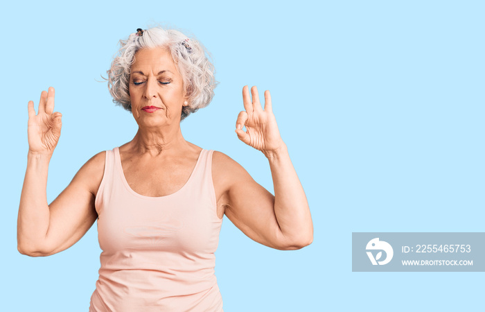 Senior grey-haired woman wearing casual clothes relax and smiling with eyes closed doing meditation gesture with fingers. yoga concept.